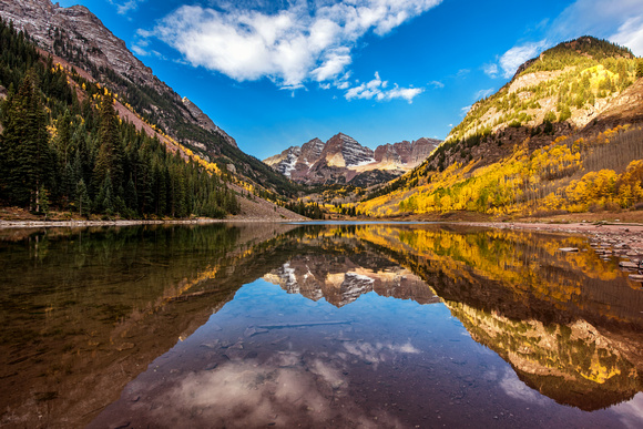 The iconic Maroon Bells reflects in Maroon Lake during peak color in Colorado