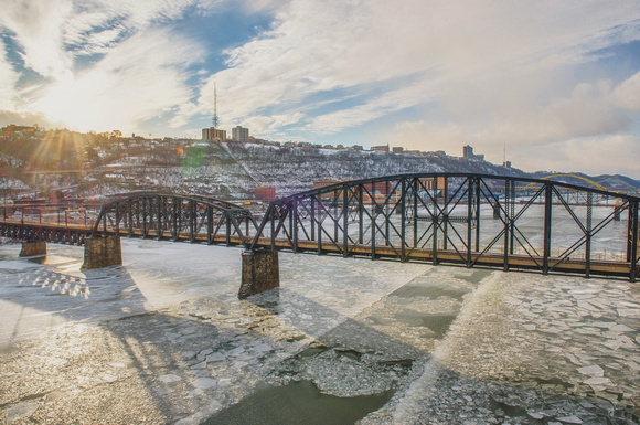 Sun flare over the Panhandle Bridge in Pittsburgh over the icy Monongahela River