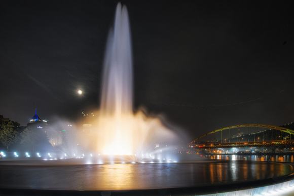 The moon rises against the fountain at Point State Park in Pittsburgh