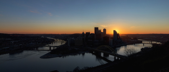 Panorama of the sun glowing behind the Pittsburgh skyline at dawn