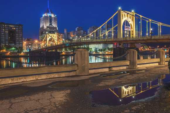 Roberto Clemente Bridge and Pittsburgh skyline reflecting in a puddle