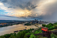 Rain showers move through Pittsburgh as a small rainbow forms over the city