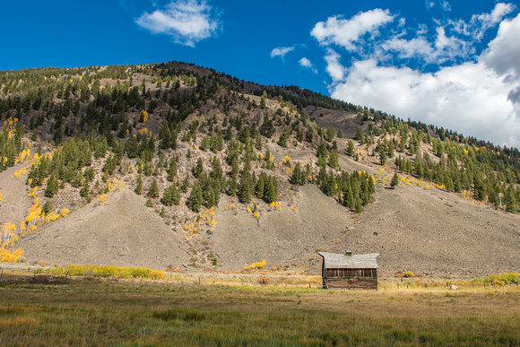A lone shack sits against a hill in the fall in Colorado