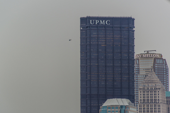 A helicopter flies by the Steel Building in Pittsburgh on a cloudy day