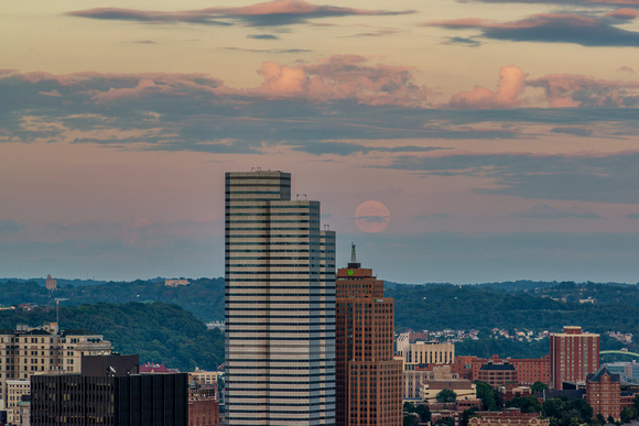 The supermoon behind the clouds of a beautiful sunset over Pittsburgh