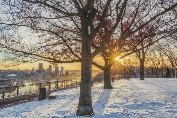 The sun rises through the trees on the West End Overlook in the winter in Pittsburgh